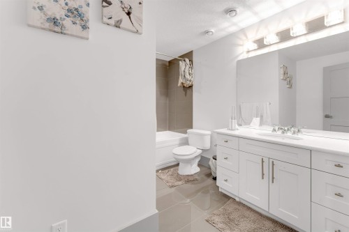 Full bathroom featuring vanity, shower / bath combination, light tile patterned flooring, and a textured ceiling - 656 180 Street, Edmonton, AB - Indoor Photo Showing Bathroom