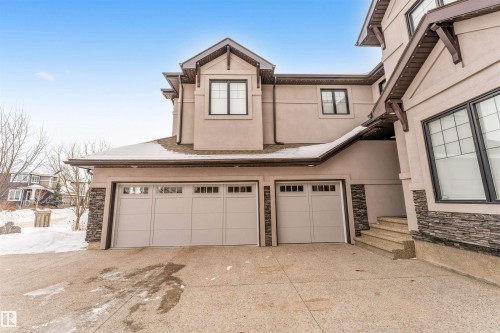 Traditional home featuring stucco siding, stone siding, an attached garage, and driveway - 656 180 Street, Edmonton, AB - Outdoor