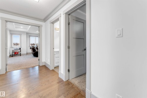 Hall with light wood-style flooring, crown molding, light colored carpet, and a tray ceiling - 656 180 Street, Edmonton, AB - Indoor Photo Showing Other Room