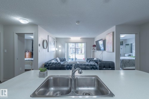 Kitchen with a textured ceiling, light countertops, and open floor plan - 107 142 Ebbers Boulevard, Edmonton, AB - Indoor Photo Showing Kitchen With Double Sink
