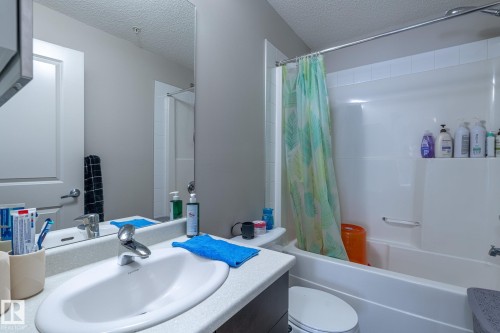 Bathroom featuring vanity, a textured ceiling, and shower / bath combination with curtain - 107 142 Ebbers Boulevard, Edmonton, AB - Indoor Photo Showing Bathroom