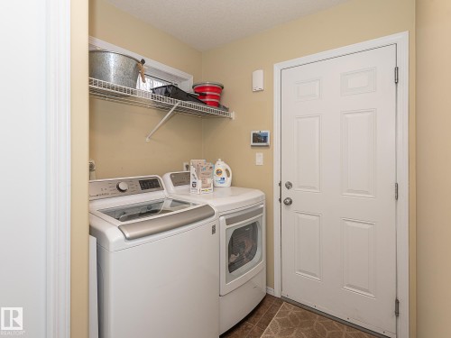 Washroom with washing machine and dryer, dark tile patterned floors, and a textured ceiling - 20628 49 Avenue, Edmonton, AB - Indoor Photo Showing Laundry Room