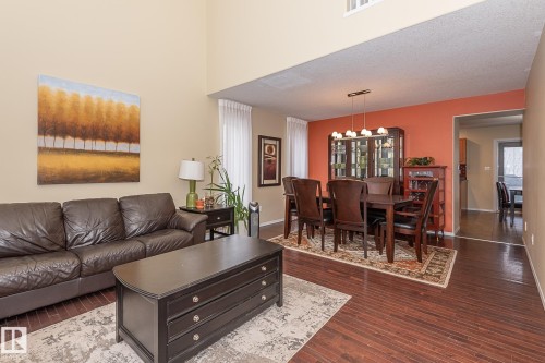 Living area with dark wood-type flooring, a chandelier, a textured ceiling, and a high ceiling - 20628 49 Avenue, Edmonton, AB - Indoor Photo Showing Living Room
