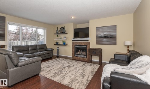 Living room featuring dark wood-type flooring, a tile fireplace, and a textured ceiling - 20628 49 Avenue, Edmonton, AB - Indoor Photo Showing Living Room With Fireplace