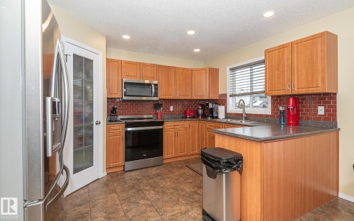 Kitchen with stainless steel appliances, a peninsula, recessed lighting, brown cabinets, and a textured ceiling - 20628 49 Avenue, Edmonton, AB - Indoor Photo Showing Kitchen