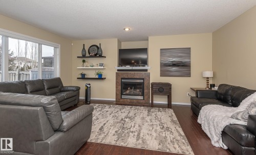 Living room featuring a tile fireplace, dark wood-type flooring, and a textured ceiling - 20628 49 Avenue, Edmonton, AB - Indoor Photo Showing Living Room With Fireplace