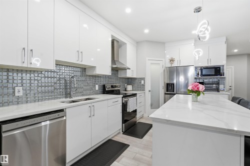 Kitchen featuring stainless steel appliances, decorative light fixtures, white cabinets, light stone counters, and recessed lighting - 452 Roberts Crescent, Leduc, AB - Indoor Photo Showing Kitchen With Double Sink With Upgraded Kitchen