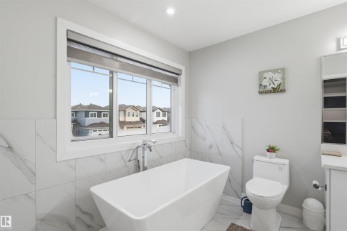 Full bathroom featuring vanity, a soaking tub, tile walls, and marble finish floors - 452 Roberts Crescent, Leduc, AB - Indoor Photo Showing Bathroom