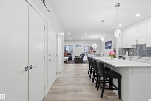 Kitchen featuring white cabinetry, light wood-style floors, a kitchen breakfast bar, recessed lighting, and hanging light fixtures - 452 Roberts Crescent, Leduc, AB - Indoor