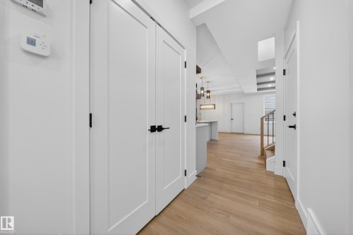 Hallway with light wood-style flooring, a chandelier, and stairway - 6115 Crawford Drive, Edmonton, AB - Indoor Photo Showing Other Room
