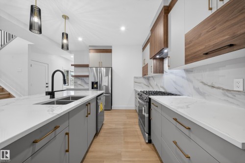 Kitchen featuring gray cabinetry, stainless steel appliances, open shelves, decorative light fixtures, and light stone counters - 6115 Crawford Drive, Edmonton, AB - Indoor Photo Showing Kitchen With Double Sink With Upgraded Kitchen