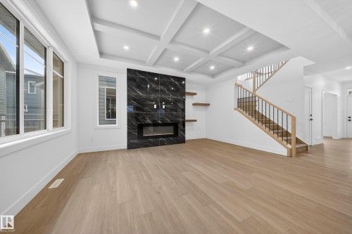 Unfurnished living room with stairs, coffered ceiling, light wood-style flooring, a fireplace, and beamed ceiling - 6115 Crawford Drive, Edmonton, AB - Indoor With Fireplace