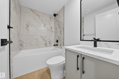 Bathroom with bathtub / shower combination, vanity, and light wood-type flooring - 6115 Crawford Drive, Edmonton, AB - Indoor Photo Showing Bathroom