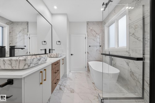 Bathroom featuring a freestanding tub, double vanity, stone wall, light marble finish flooring, and recessed lighting - 6115 Crawford Drive, Edmonton, AB - Indoor Photo Showing Bathroom
