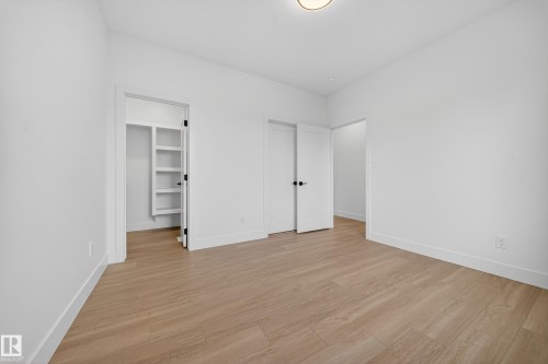 Unfurnished bedroom with a walk in closet and light wood-style floors - 6115 Crawford Drive, Edmonton, AB - Indoor Photo Showing Other Room
