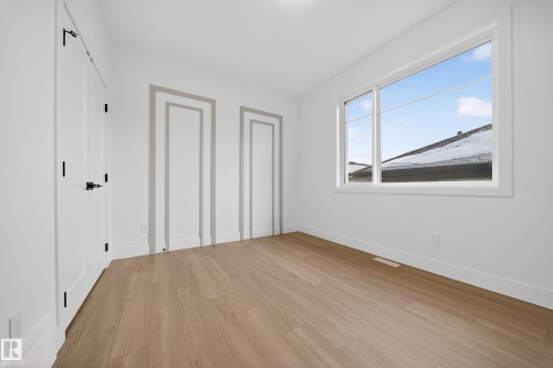 Unfurnished bedroom with light wood-type flooring and two closets - 6115 Crawford Drive, Edmonton, AB - Indoor Photo Showing Other Room