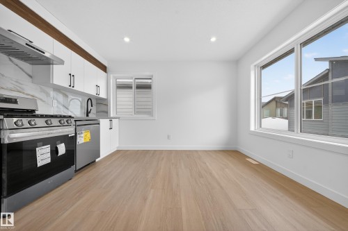 Kitchen featuring white cabinets, appliances with stainless steel finishes, light wood finished floors, recessed lighting, and backsplash - 6115 Crawford Drive, Edmonton, AB - Indoor