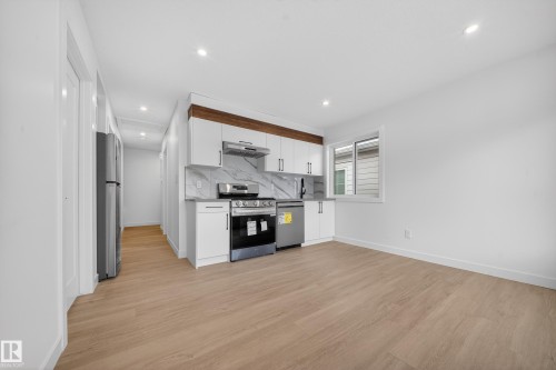 Kitchen featuring white cabinets, appliances with stainless steel finishes, light wood-style floors, decorative backsplash, and recessed lighting - 6115 Crawford Drive, Edmonton, AB - Indoor Photo Showing Kitchen