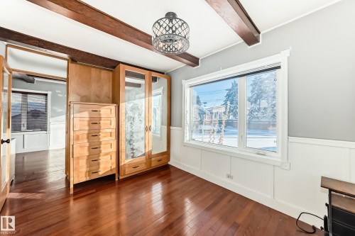 Unfurnished bedroom featuring a wainscoted wall, beam ceiling, wood-type flooring, and a decorative wall - 10115 104, Westlock, AB - Indoor Photo Showing Other Room