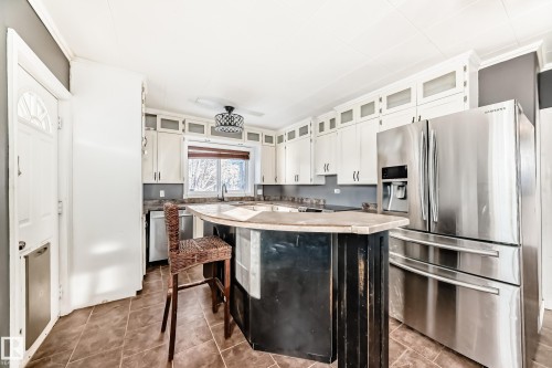 Kitchen with appliances with stainless steel finishes, white cabinets, light countertops, a kitchen bar, and glass insert cabinets - 10115 104, Westlock, AB - Indoor Photo Showing Kitchen
