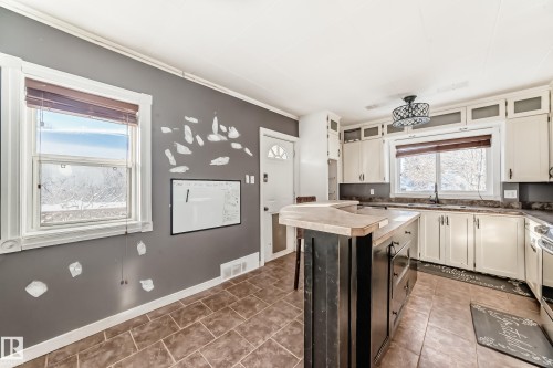 Kitchen featuring crown molding, white cabinets, a kitchen island, and a breakfast bar - 10115 104, Westlock, AB - Indoor Photo Showing Kitchen
