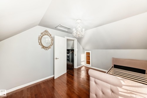 Unfurnished bedroom featuring lofted ceiling, dark wood-type flooring, a chandelier, and attic access - 10115 104, Westlock, AB - Indoor Photo Showing Other Room