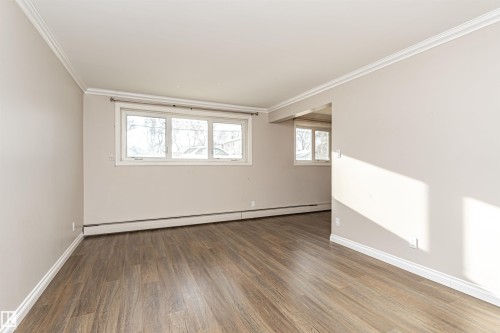 Empty room with wood finished floors, a baseboard radiator, and crown molding - 102 10735 81 Avenue, Edmonton, AB - Indoor Photo Showing Other Room