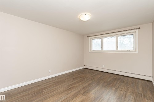 Unfurnished room with wood finished floors and a baseboard heating unit - 102 10735 81 Avenue, Edmonton, AB - Indoor Photo Showing Other Room