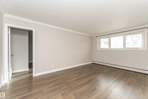 Spare room with wood finished floors, ornamental molding, and baseboard heating - 102 10735 81 Avenue, Edmonton, AB - Indoor Photo Showing Other Room