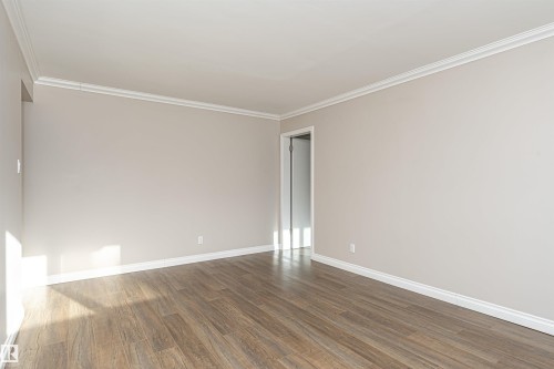 Unfurnished room with dark wood-type flooring and ornamental molding - 102 10735 81 Avenue, Edmonton, AB - Indoor Photo Showing Other Room
