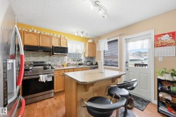 Kitchen with appliances with stainless steel finishes, a kitchen island, a kitchen breakfast bar, light countertops, and under cabinet range hood - 