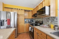 Kitchen with appliances with stainless steel finishes, light countertops, under cabinet range hood, tasteful backsplash, and a textured ceiling - 