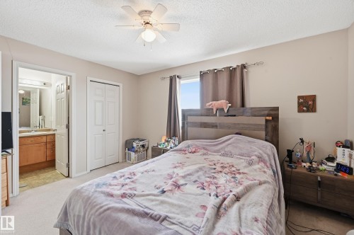 Bedroom featuring light carpet, a closet, a textured ceiling, ceiling fan, and connected bathroom - 3010 32 Avenue Nw, Edmonton, AB - Indoor Photo Showing Bedroom