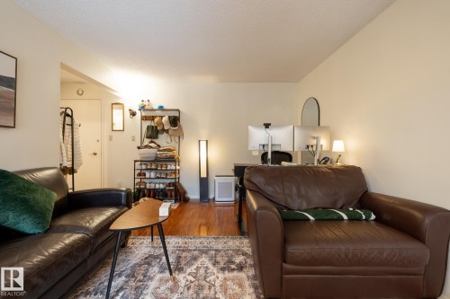 Living room featuring wood finished floors and a textured ceiling - 307 5730 Riverbend Road, Edmonton, AB - Indoor Photo Showing Living Room