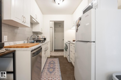 Kitchen featuring white appliances, white cabinets, and backsplash - 307 5730 Riverbend Road, Edmonton, AB - Indoor Photo Showing Kitchen