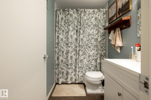 Bathroom featuring vanity, curtained shower, and dark tile patterned flooring - 307 5730 Riverbend Road, Edmonton, AB - Indoor Photo Showing Bathroom