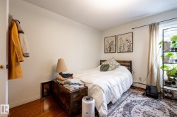Bedroom with wood finished floors, a baseboard radiator, and a textured ceiling - 