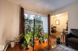 Living room featuring a textured ceiling, dark wood finished floors, a baseboard heating unit, and a chandelier - 