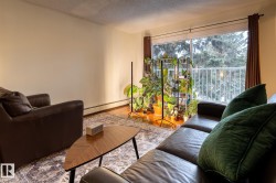 Living area featuring a baseboard heating unit, a textured ceiling, and wood finished floors - 