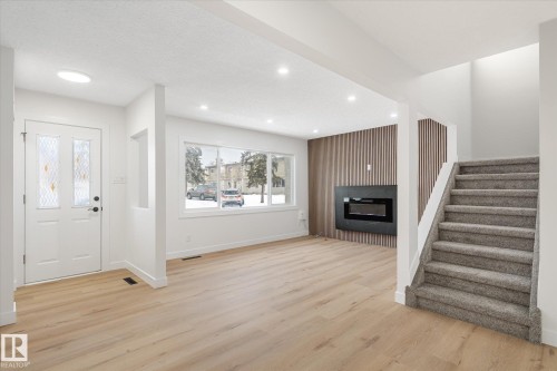 Foyer entrance featuring light wood-type flooring, a fireplace, recessed lighting, and stairway - 5105 106A Street, Edmonton, AB - Indoor With Fireplace