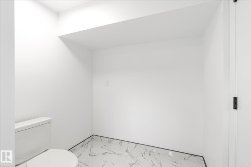 Half bathroom with toilet and marble finish flooring - 5105 106A Street, Edmonton, AB - Indoor Photo Showing Bathroom