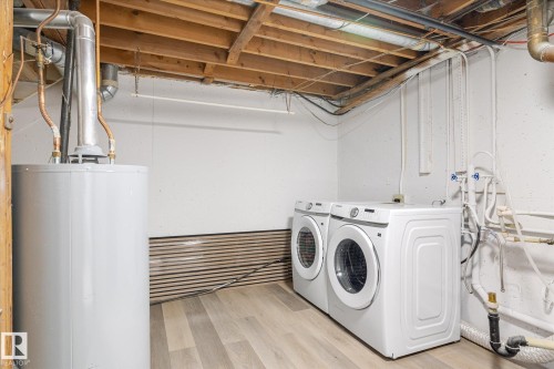 Laundry room with water heater, wood finished floors, and separate washer and dryer - 5105 106A Street, Edmonton, AB - Indoor Photo Showing Laundry Room