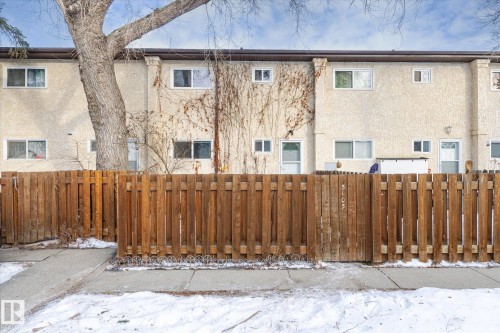 Snow covered house featuring a fenced front yard, stucco siding, and a gate - 5105 106A Street, Edmonton, AB - Outdoor