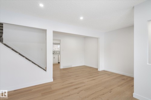 Basement with light wood-style flooring, a textured ceiling, and stairs - 5105 106A Street, Edmonton, AB - Indoor Photo Showing Other Room