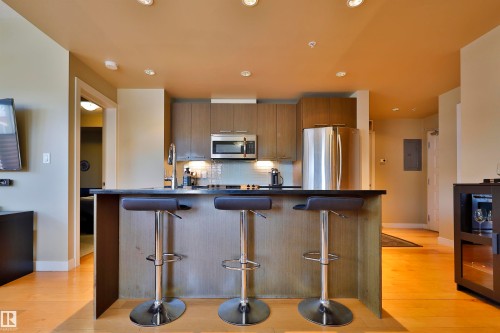 Kitchen with dark countertops, stainless steel appliances, backsplash, light wood-style floors, and recessed lighting - 203 9908 84 Avenue, Edmonton, AB - Indoor Photo Showing Kitchen With Stainless Steel Kitchen With Upgraded Kitchen