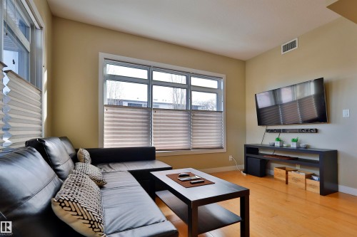 Living room with light wood-style flooring and baseboards - 203 9908 84 Avenue, Edmonton, AB - Indoor Photo Showing Living Room