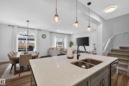 Kitchen with dark wood-style flooring, light stone countertops, hanging light fixtures, open floor plan, and a chandelier - 2098 Graydon Hill Crescent, Edmonton, AB - Indoor Photo Showing Kitchen With Double Sink