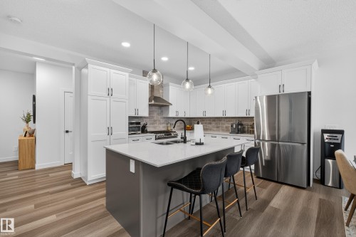 Kitchen featuring freestanding refrigerator, white cabinetry, pendant lighting, an island with sink, and a breakfast bar - 2098 Graydon Hill Crescent, Edmonton, AB - Indoor Photo Showing Kitchen With Stainless Steel Kitchen With Upgraded Kitchen