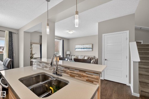 Kitchen featuring light countertops, hanging light fixtures, open floor plan, a textured ceiling, and dark wood-style floors - 5910 Anthony Crescent, Edmonton, AB - Indoor Photo Showing Kitchen With Double Sink