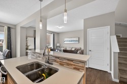 Kitchen featuring light countertops, hanging light fixtures, open floor plan, a textured ceiling, and dark wood-style floors - 
